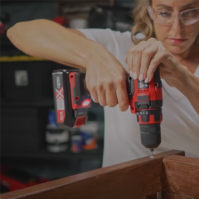 A woman is screwing a screw into wood