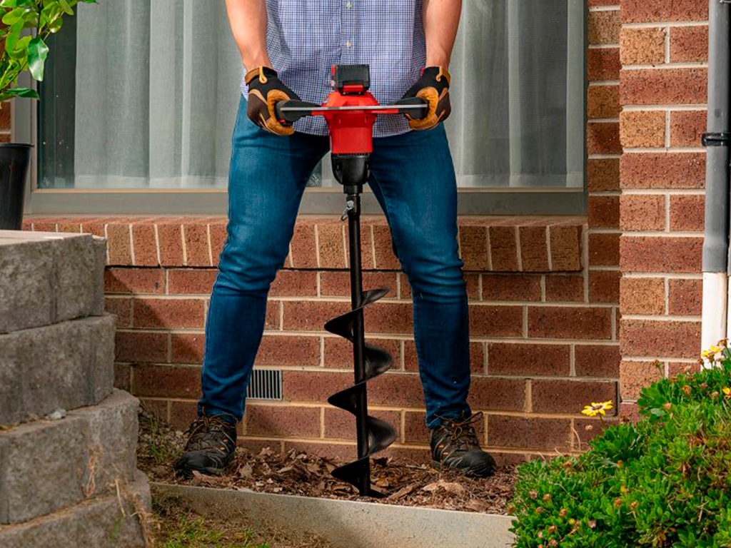 A man is drilling a hole with a cordless auger